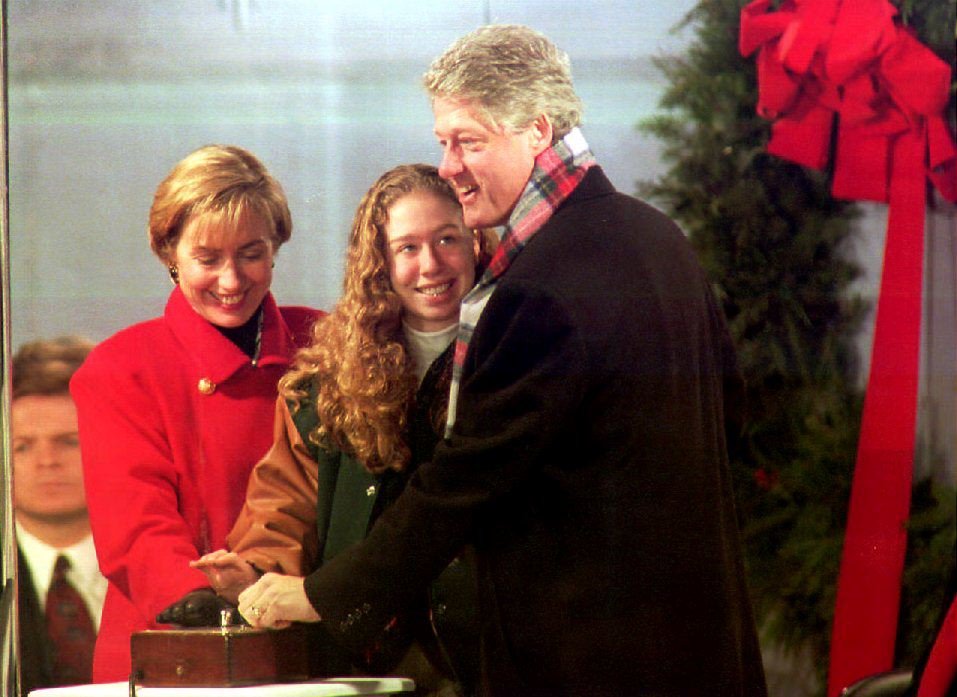 U.S. President Bill Clinton joins First Lady Hillary Clinton and Chelsea Clinton in pressing the button that lights the National Christmas Tree 09 December 1993. Some 9,000 people watched as the tree was lit with 10,000 lights. (Photo credit should read LUKE FRAZZA/AFP/Getty Images)