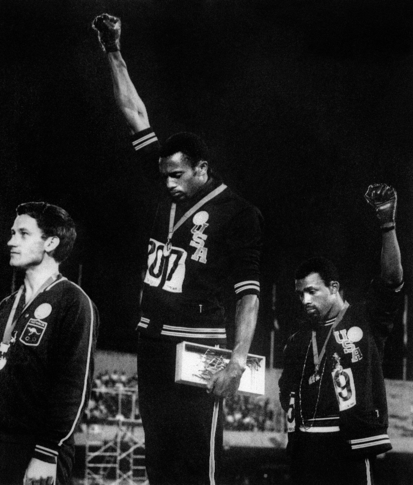 US athletes Tommie Smith (C) and John Carlos (R) raise their gloved fists in the Black Power salute to express their opposition to racism in the USA during the US national anthem, after receiving their medals 17 October 1968 for first and third place in the men's 200m event at the Mexico Olympic Games. At left is Peter Norman of Australia who took second place. (Photo credit should read OFF/AFP/Getty Images)