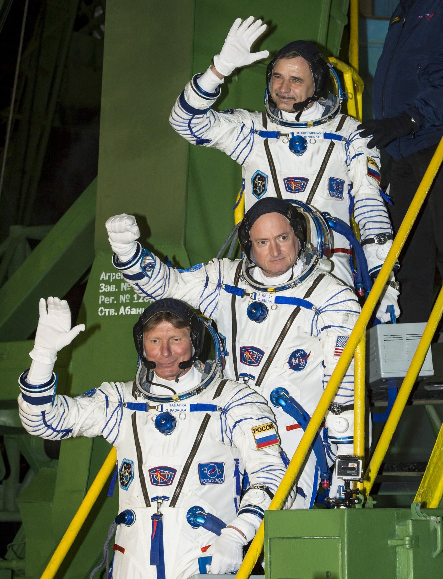 Expedition 43 Russian Cosmonaut Mikhail Kornienko of the Russian Federal Space Agency (Roscosmos), top, NASA Astronaut Scott Kelly, center, and Russian Cosmonaut Gennady Padalka of Roscosmos wave farewell as they board the Soyuz TMA-16M spacecraft ahead of their launch to the International Space Station, Friday, March 27, 2015 in Baikonor, Kazakhstan. As the one-year crew, Kelly and Kornienko will return to Earth on Soyuz TMA-18M in March 2016. Photo Credit (NASA/Bill Ingalls)