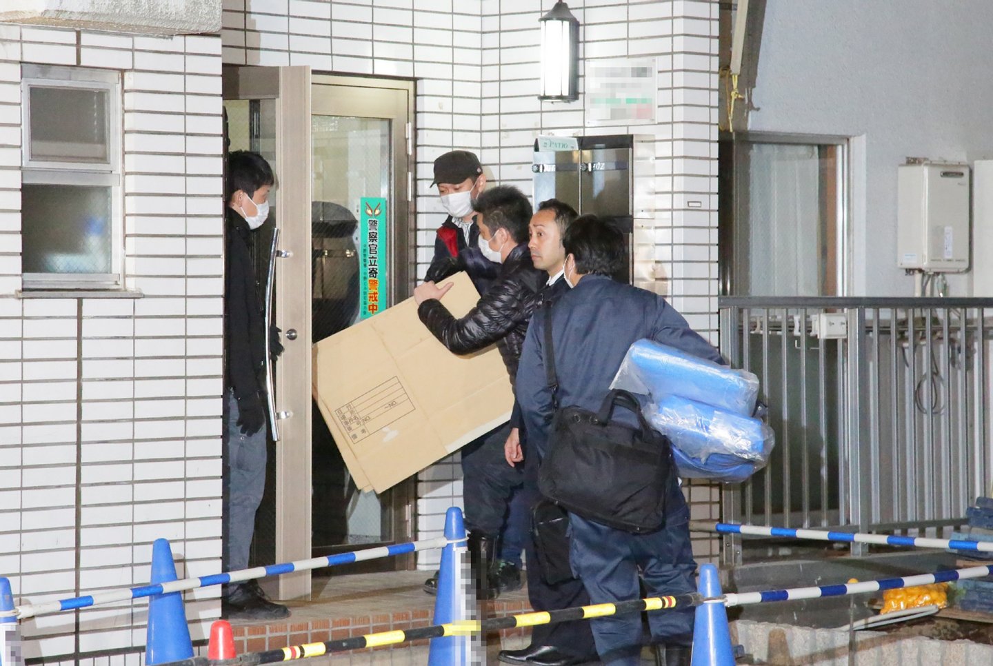 Police investigators enter an the apartment of the suspect believed to be lived with a girl in Tokyo on March 28, 2016. A Japanese girl who vanished two years ago has returned home after escaping from the apartment of the university student who had held her captive, police and local media said March 28. / AFP / JIJI PRESS / JIJI PRESS (Photo credit should read JIJI PRESS/AFP/Getty Images)