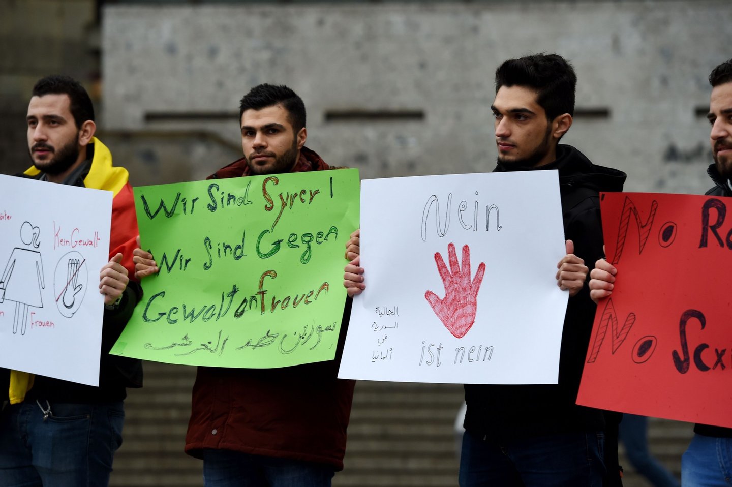 Refugees from Syria hold a sign reading "we are syrians-we are against violence against women" as they demonstrate against violence at the Cologne main train station in Cologne, western Germany on January 16, 2016 where violence against women were perpetrated on New Year's Eve. / AFP / PATRIK STOLLARZ (Photo credit should read PATRIK STOLLARZ/AFP/Getty Images)