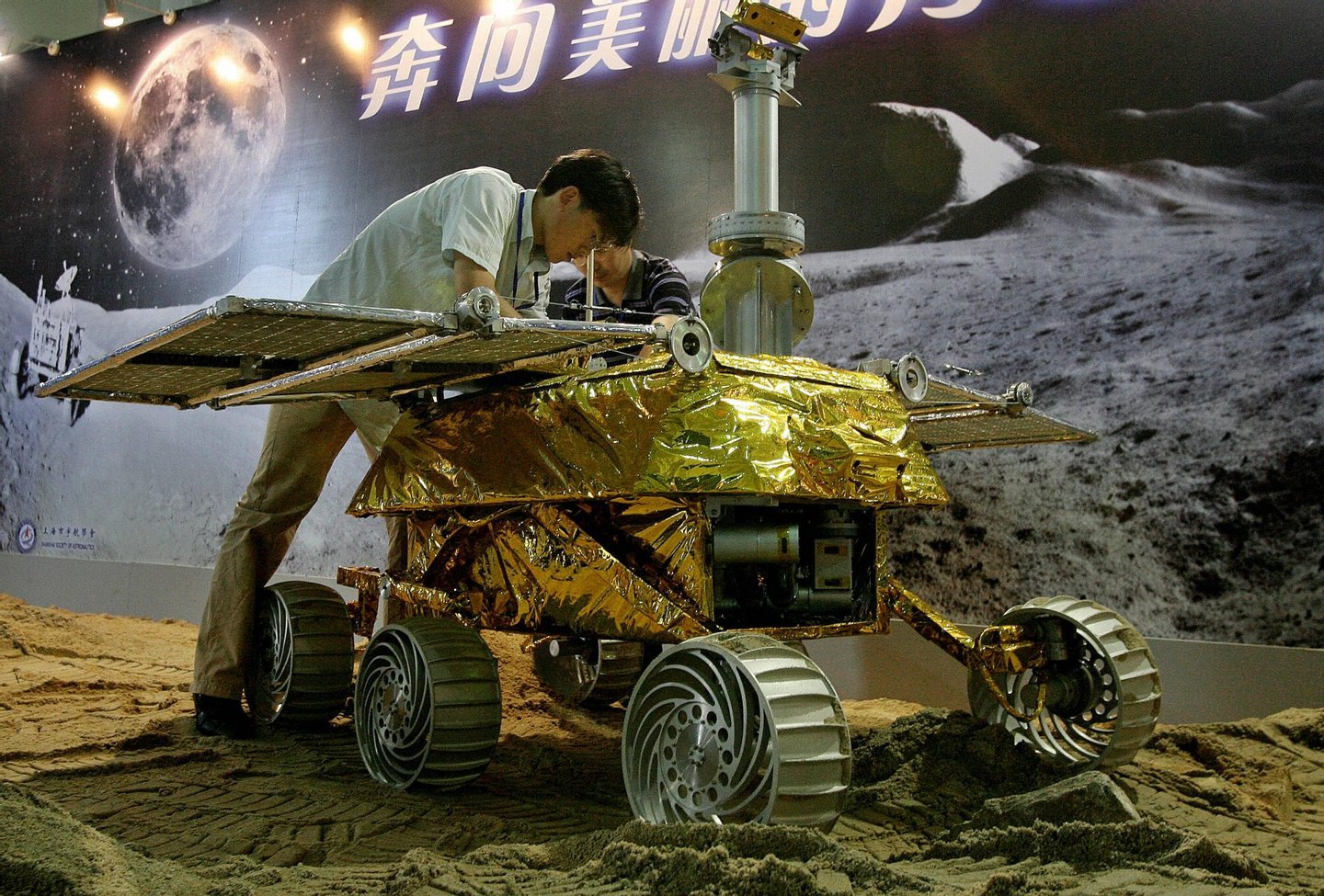 Shanghai, CHINA: Chinese technicians work on the MR-2 lunar vehicle, built by the Shanghai Aerospace Administration and on display at an aviation and space exhibition in Shanghai, 05 July 2007. The lunar vehicle robot, which can move at speeds up to 200 meters per hour, will start its exploration with China 's first moon landing probe as the second part of China's three- phase moon exploration program. State media reported China plans a manned lunar mission by 2024 that will include a walk on the moon's surface. AFP PHOTO/Mark RALSTON (Photo credit should read MARK RALSTON/AFP/Getty Images)