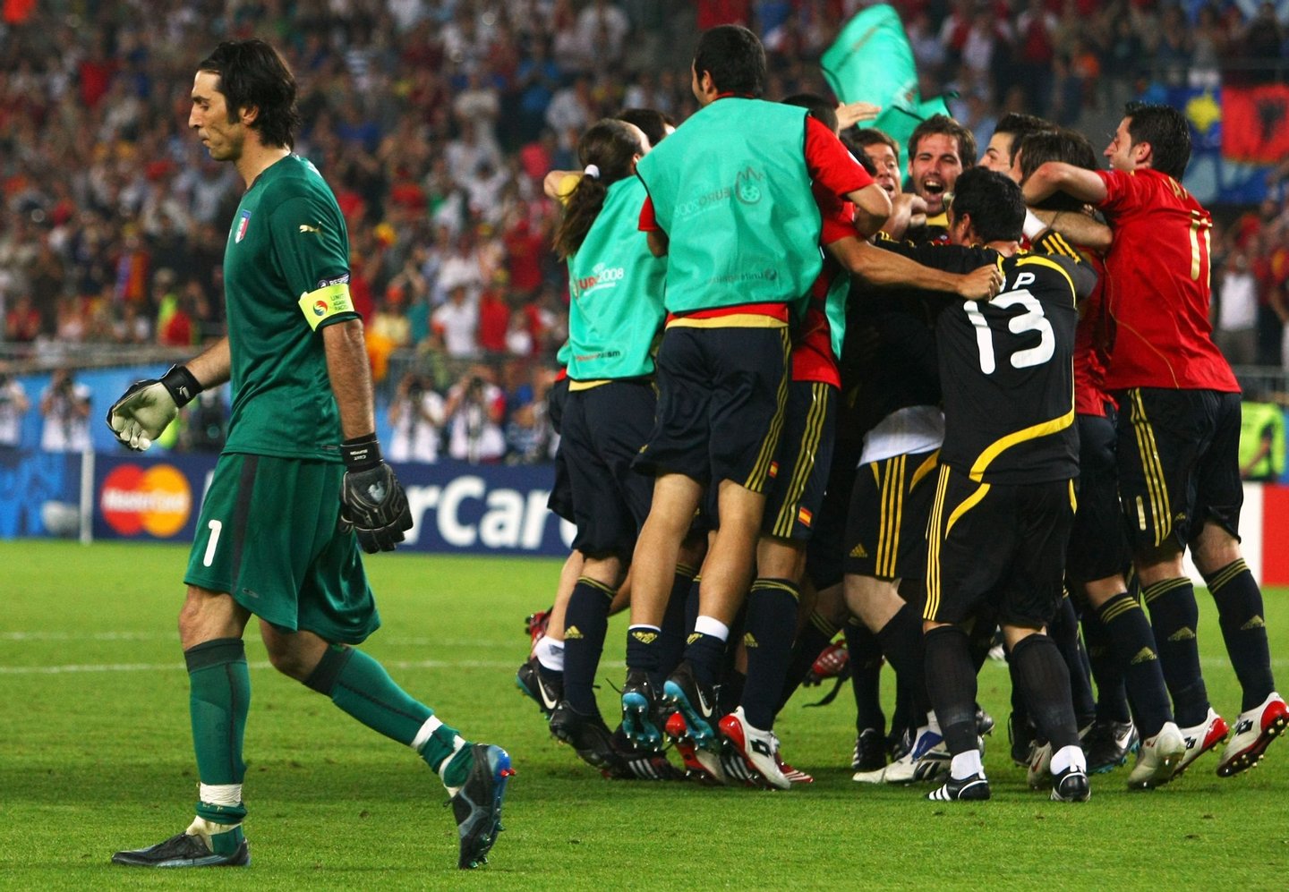VIENNA, AUSTRIA - JUNE 22: Gianluigi Buffon (L) of Italy walks off dejected as Spanish players celebrate after Cesc Fabregas of Spain shoots and scores the winning penalty in the shoot out during the UEFA EURO 2008 Quarter Final match between Spain and Italy at Ernst Happel Stadion on June 22, 2008 in Vienna, Austria. (Photo by Clive Rose/Getty Images)
