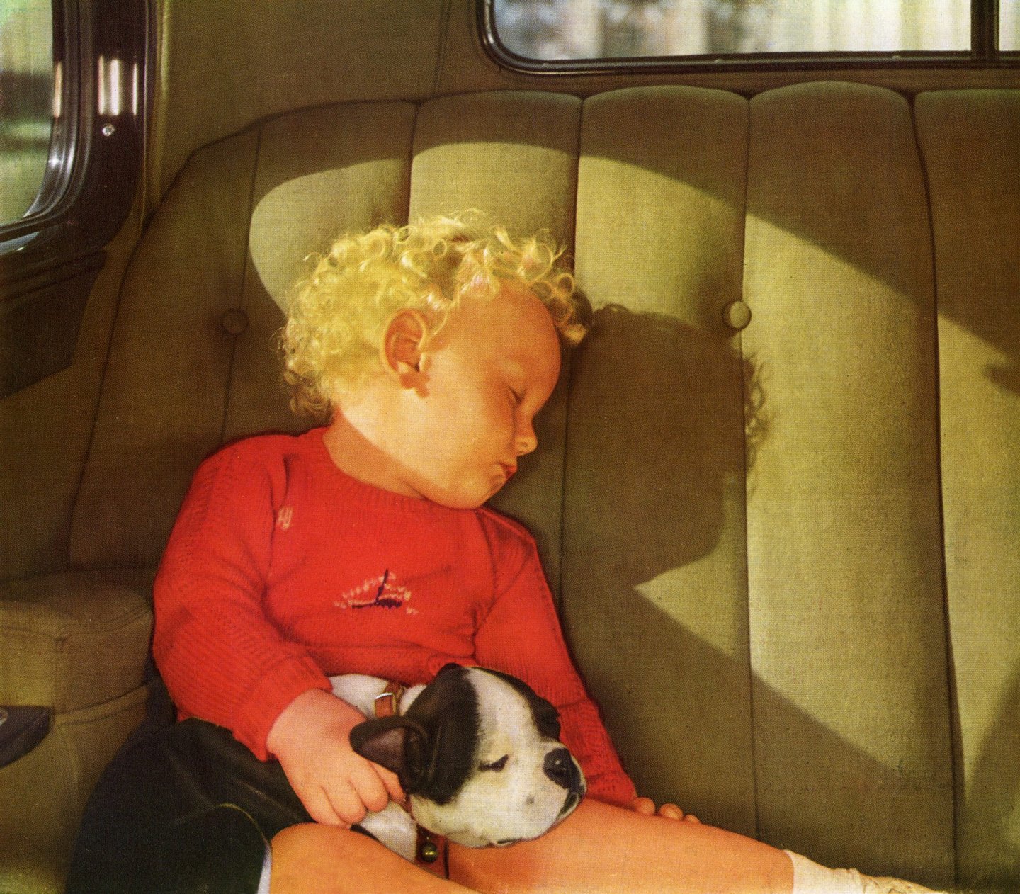 Vintage illustration of a blond little boy sleeping with his dog in the back seat of a car, 1930s. Screen print. (Illustration by GraphicaArtis/Getty Images)