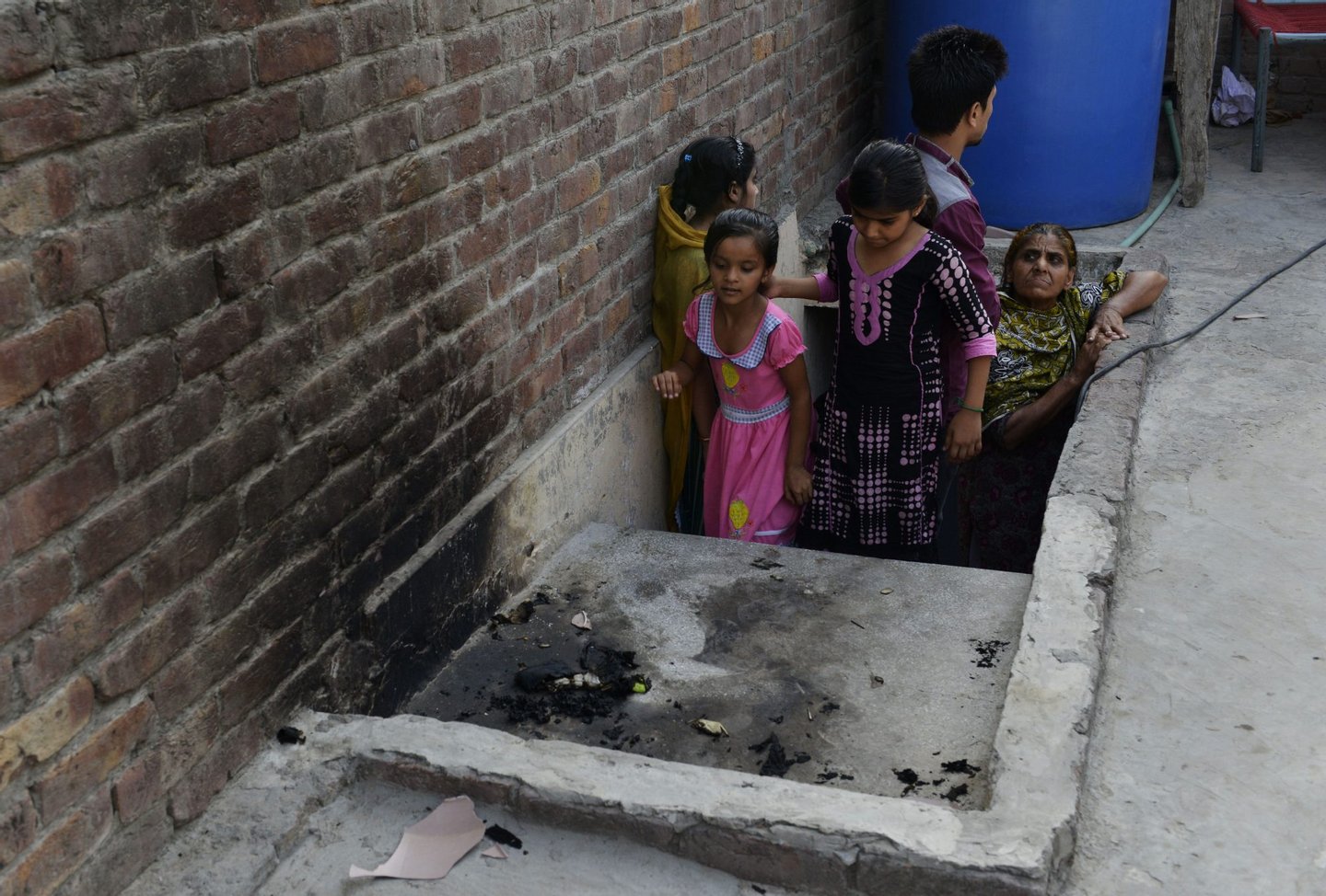 Pakistani residents stand at the site where a teenager was burnt alive by her mother in Lahore on June 8, 2016. A Pakistani mother on June 8 burnt her 16-year-old daughter alive for marrying a man of her own choice, before running out her street to tell neighbours she had killed the teen for bringing shame to the family. It was the third so-called "honour killing" in the South Asian country in as many months, and a rare example of the crime being carried out by a woman. / AFP / ARIF ALI (Photo credit should read ARIF ALI/AFP/Getty Images)