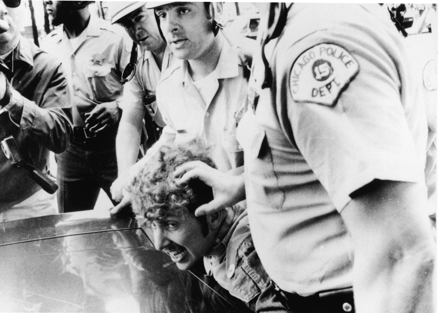 Officers from the Chicago Police Department push a protestor's head against the hood of a car as they restrain him after he climbed onto a wooden barricade near the Democratic headquarters of the 1968 Democratic National Convention and waved a Vietcong flag during anti-Vietnam War demonstrations, Chicago, Illinois, August 26, 1968. (Photo by APA/Getty Images)