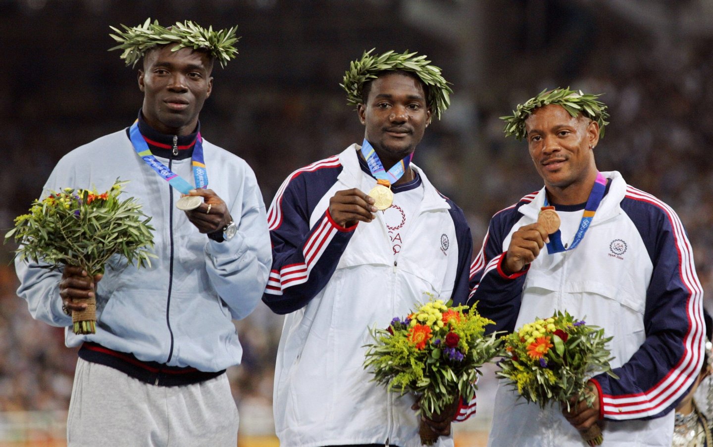 ATHENS, Greece: Men's 100m gold medal winner Justin Gatlin of the USA (C), silver winner Francis Obikwelu of Portugal (L), and bronze winner Maurice Greene of the USA stand on the winners' podium, 23 August 2004, during the Olympic Games athletics competitions at the Olympic Stadium in Athens. AFP PHOTO/TOSHIFUMI KITAMURA (Photo credit should read TOSHIFUMI KITAMURA/AFP/Getty Images)