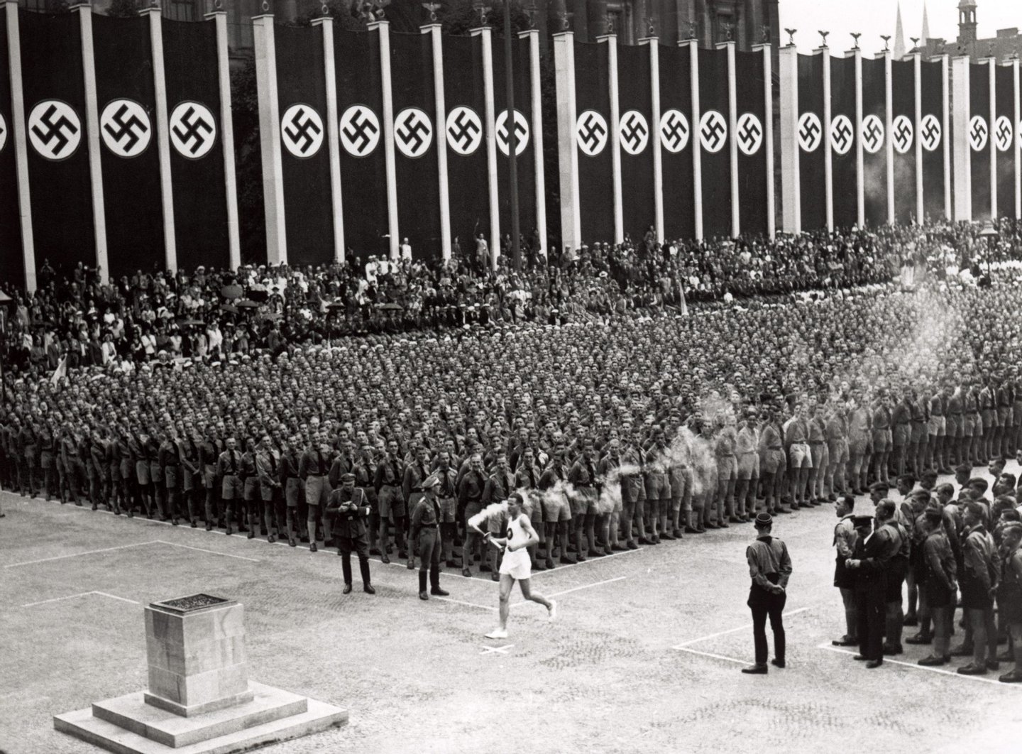 The Olympic torch is carried into the stadium during the opening ceremonies of the XI Olympic Games at the Olympic Stadium in Berlin, Germany, on August 1, 1936. (Photo by Getty Images)