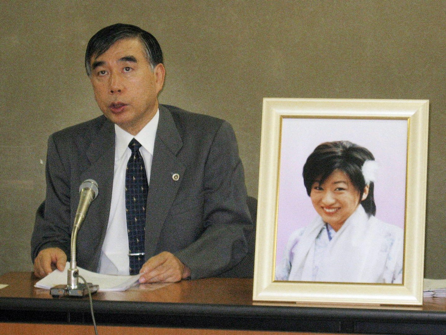 TO GO WITH STORY "FINANCE-ECONOMY-JAPAN-HEALTH-PSYCHOLOGY" by PATRICE NOVOTNY Japanese lawyer Hiroshi Kawahito speaks at a press conference in Tokyo on October 17, 2008, while a portrait of Japanese nurse Ai Takahashi, a victim of "karoshi" or death by overwork is displayed. Pushed to their limits, thousands of Japanese are literally working themselves to death each year, a scourge the Asian power has started to address but is seen getting worse in the global economic crisis. AFP PHOTO / JIJI PRESS (Photo credit should read STR/AFP/Getty Images)