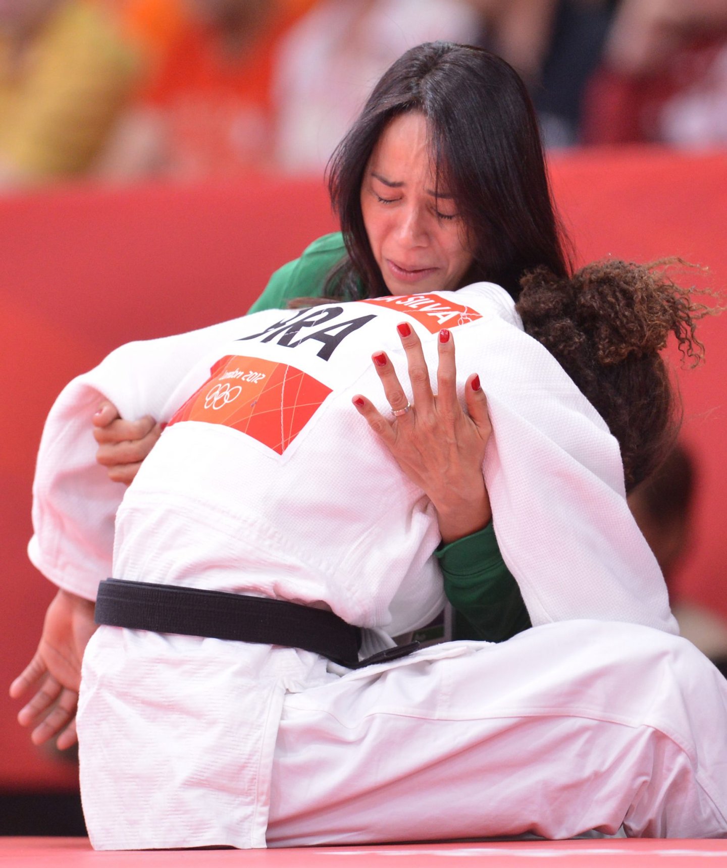 Brazil's Rafaela Silva commissarates with her coach Campos Rosicleia, after losing against Hungary's Hedvig Karakas during their women's -57kg judo contest match of the London 2012 Olympic Games on July 30, 2012 ExCel arena in London. AFP PHOTO / JOHANNES EISELE (Photo credit should read JOHANNES EISELE/AFP/GettyImages)