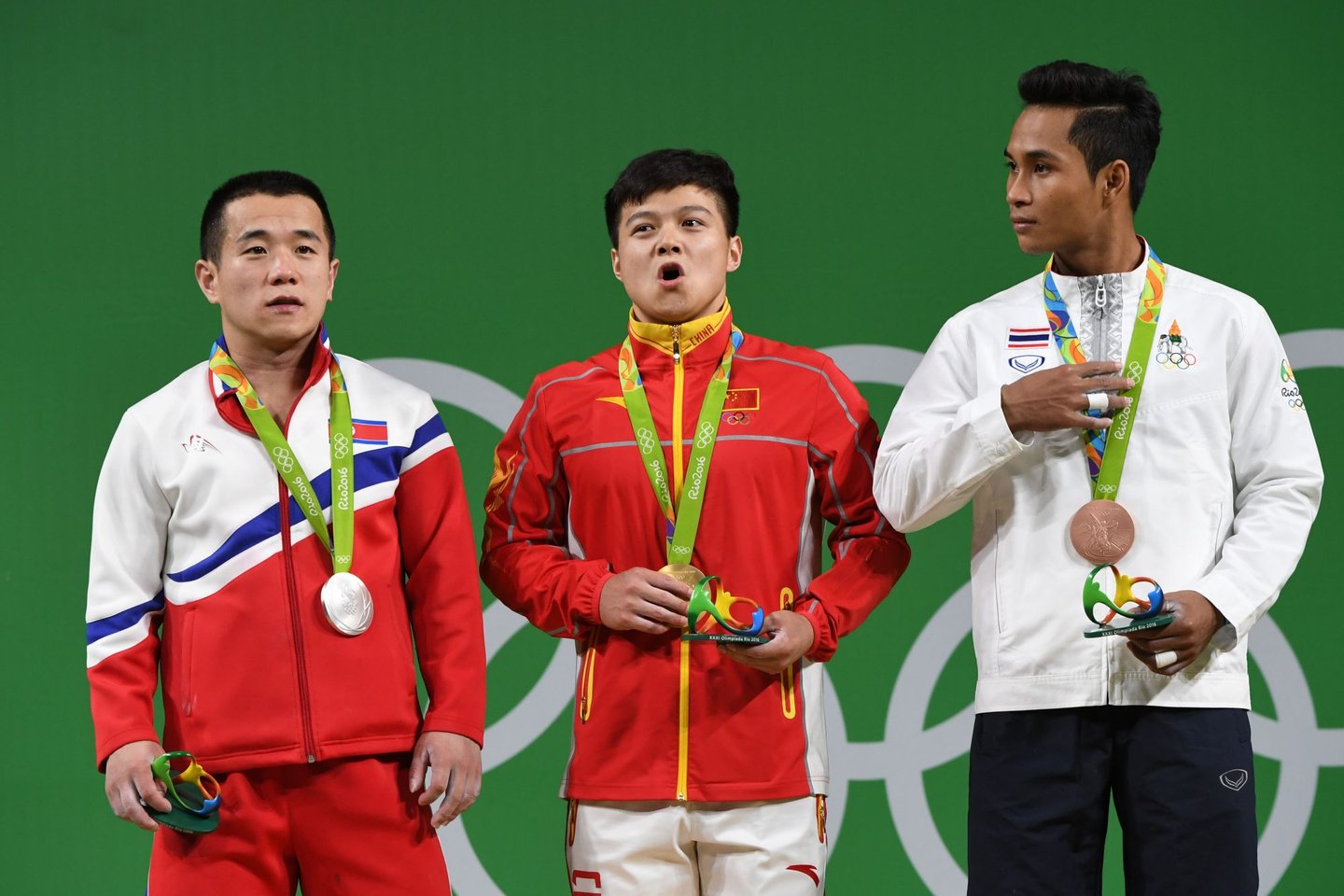 China's gold medallist Long Qingquan (C, North Korea's silver medallist Om Yun Chol (L) and Thailand's bronze medalist Sinphet Kruaithong pose with their medals on the podium during the men's 56kg weightlifting event at the Rio 2016 Olympic games in Rio de Janeiro on August 7, 2016. / AFP / GOH Chai Hin (Photo credit should read GOH CHAI HIN/AFP/Getty Images)