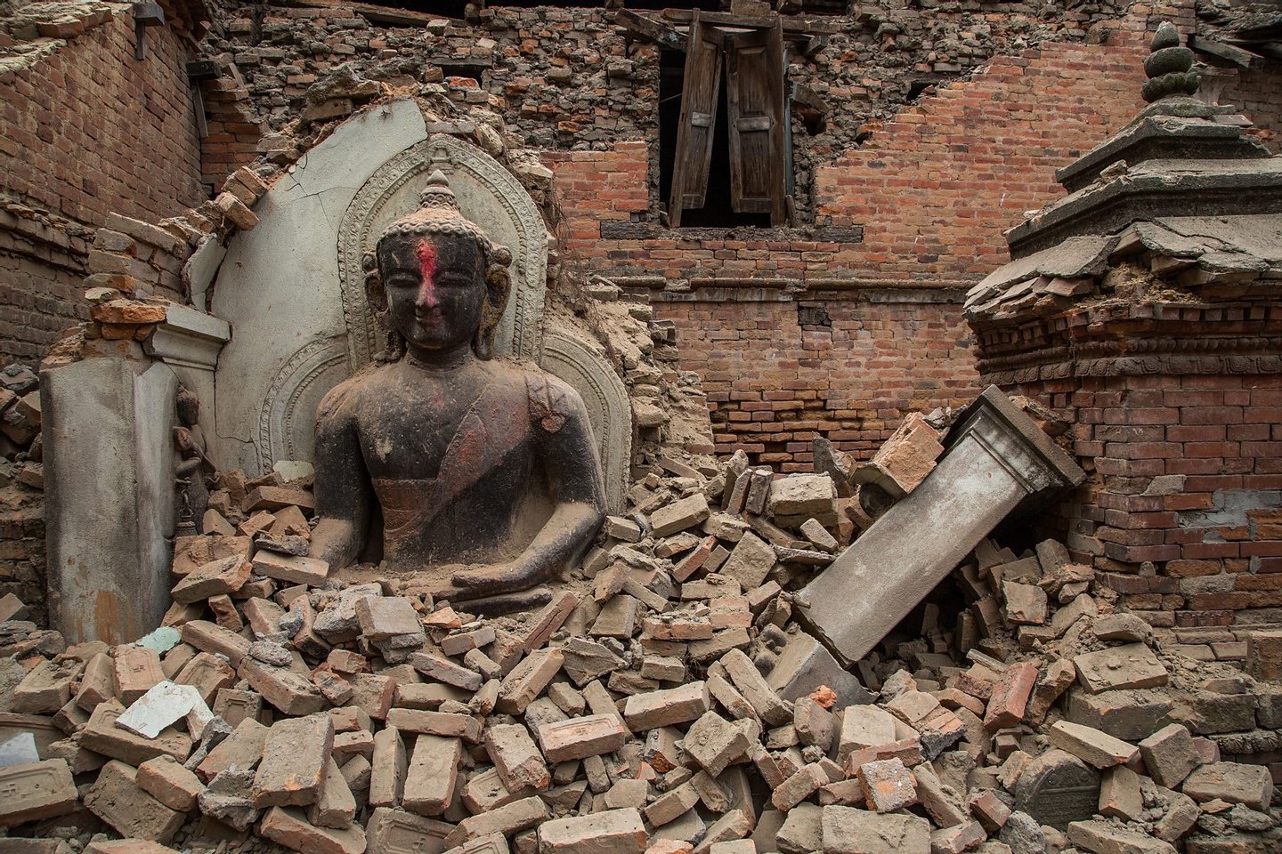 BHAKTAPUR, NEPAL - APRIL 26: A Buddha statue is surrounded by debris from a collapsed temple in the UNESCO world heritage site of Bhaktapur on April 26, 2015 in Bhaktapur, Nepal. A major 7.8 earthquake hit Kathmandu mid-day on Saturday, and was followed by multiple aftershocks that triggered avalanches on Mt. Everest that buried mountain climbers in their base camps. Many houses, buildings and temples in the capital were destroyed during the earthquake, leaving thousands dead or trapped under the debris as emergency rescue workers attempt to clear debris and find survivors. (Photo by Omar Havana/Getty Images)