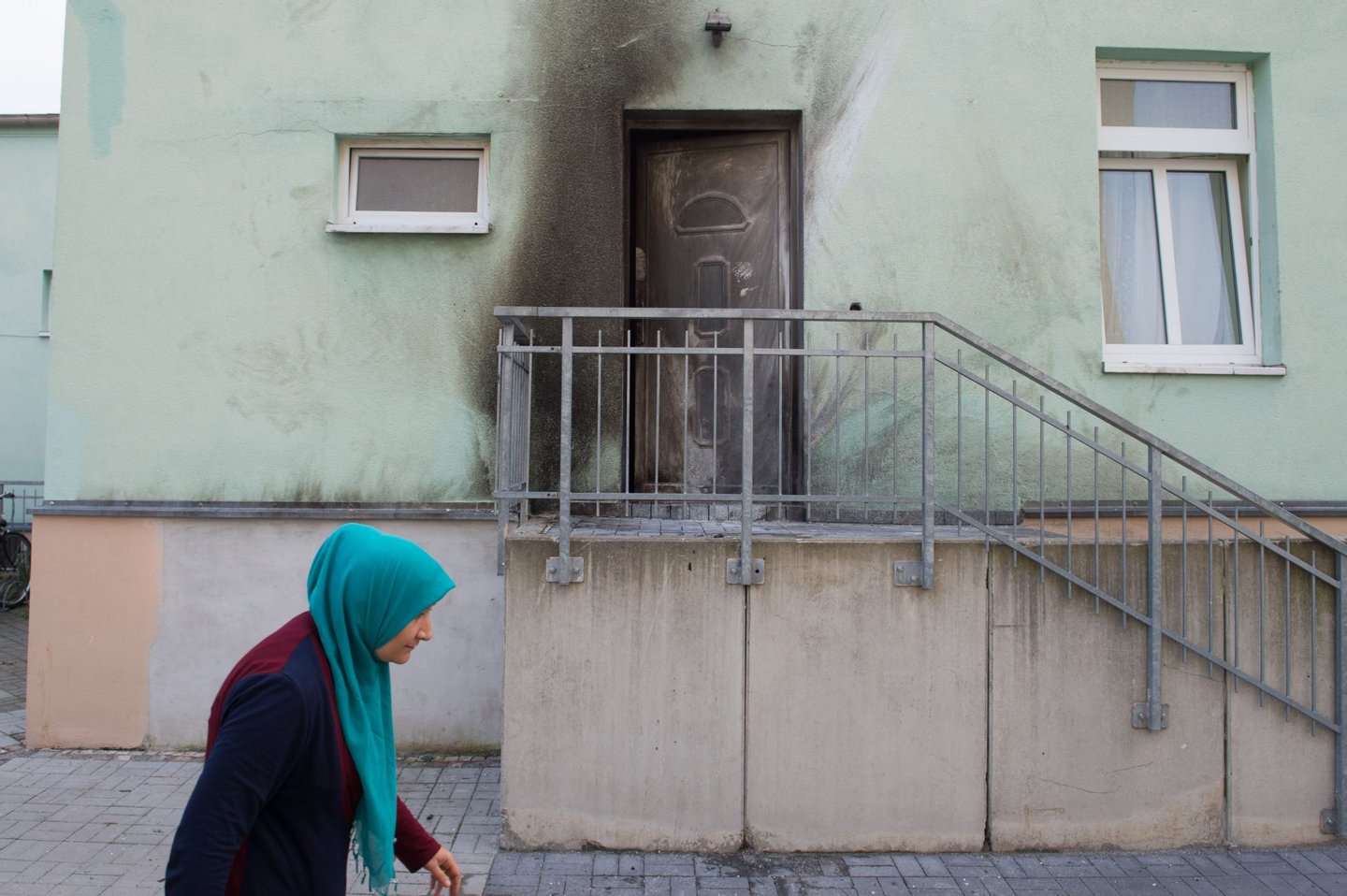 A woman wearing a headscarf walks past the entrance to the Fatih Camii Mosque in Dresden, eastern Germany, where traces of smoke can be seen after a bomb attack. Bomb attacks hit a mosque and a congress centre in the eastern German city of Dresden, police said, addding that they suspected a xenophobic and nationalist motive. No-one was injured in the twin explosives attacks late Monday, September 26, 2016 in the city that has become a hotspot for far-right protests amid Germany's huge migrant influx. / AFP / dpa / Sebastian Kahnert / Germany OUT (Photo credit should read SEBASTIAN KAHNERT/AFP/Getty Images)