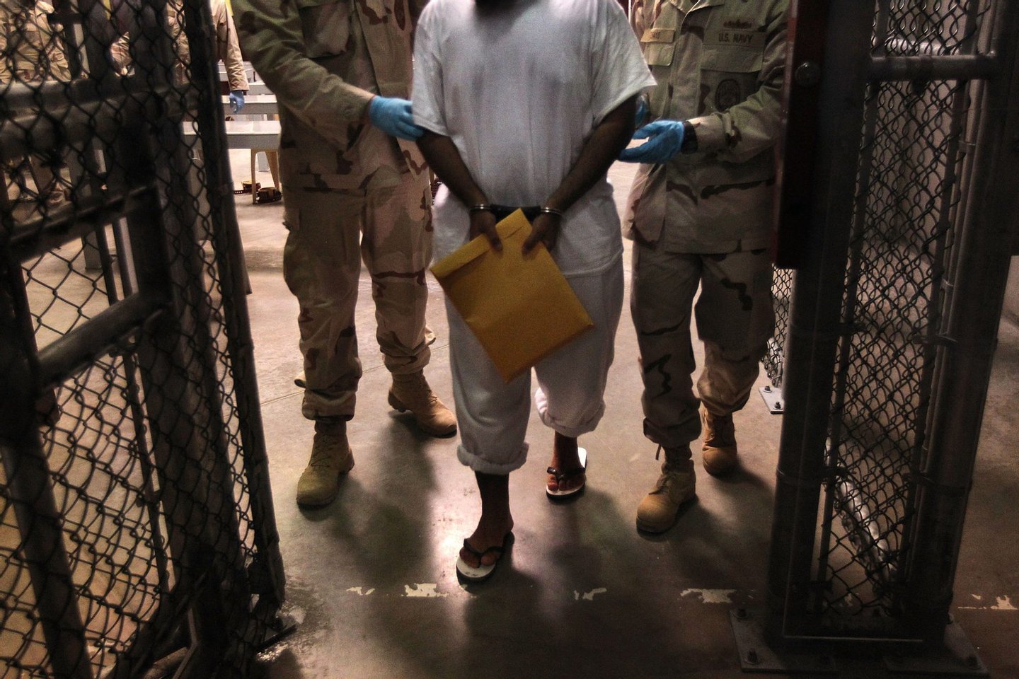 GUANTANAMO BAY, CUBA - MARCH 30: (EDITORS NOTE: Image has been reviewed by the U.S. Military prior to transmission.) U.S. Navy guards escort a detainee after a "life skills" class held for prisoners at Camp 6 in the Guantanamo Bay detention center on March 30, 2010 in Guantanamo Bay, Cuba. U.S. President Barack Obama pledged to close the facility by early 2010 but has struggled to transfer, try or release the remaining detainees from the facility, located on the U.S. Naval Base at Guantanamo Bay, Cuba. (Photo by John Moore/Getty Images)