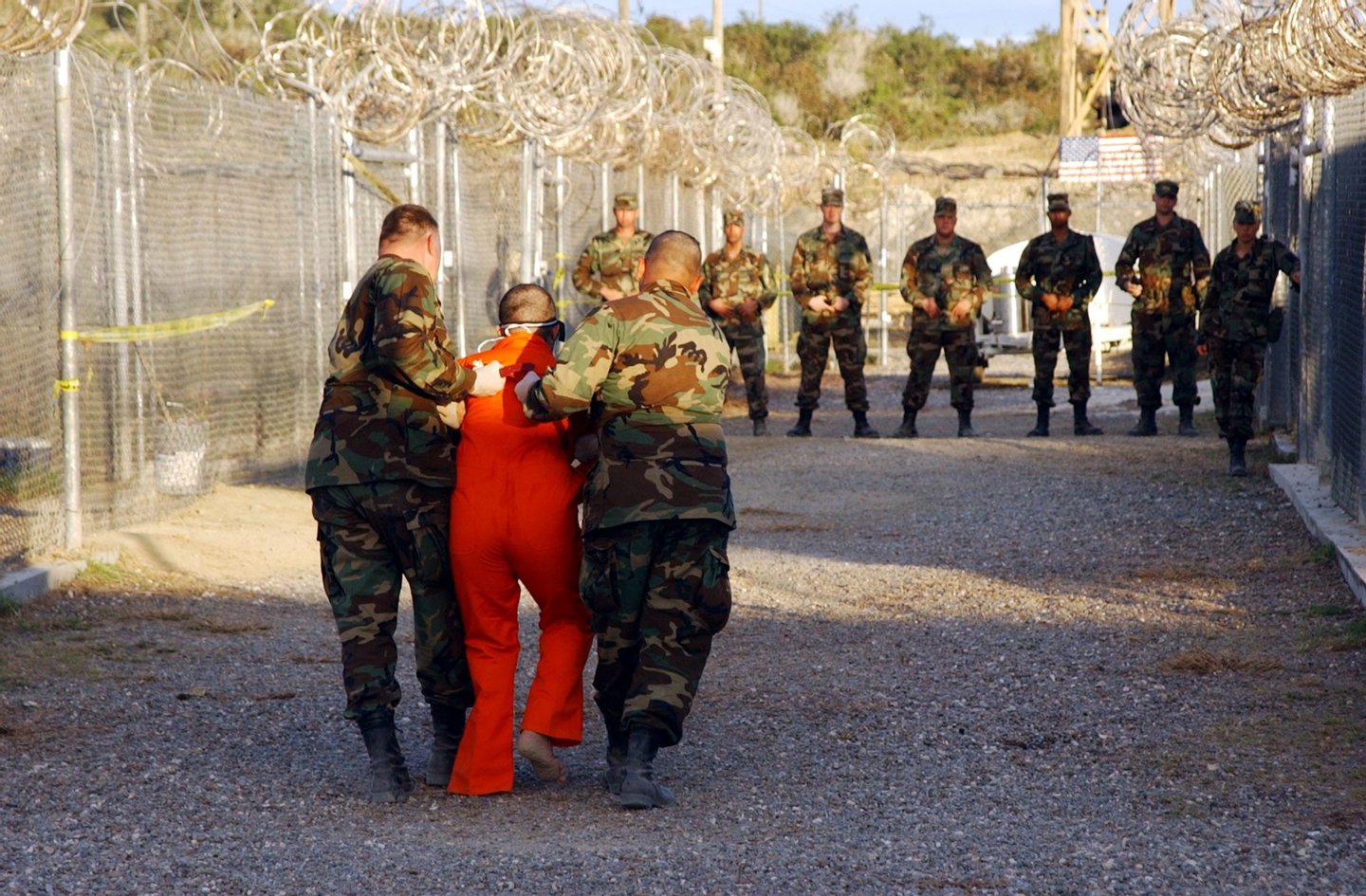 399884 02: U.S. Army Military Police escort a detainee to his cell January 11, 2001 in Camp X-Ray at Naval Base Guantanamo Bay, Cuba, during in-processing to the temporary detention. The detainees will be given a basic physical exam by a doctor, to include a chest x-ray and blood samples drawn to assess their health, the military said. The U.S. Department of Defense released the photo January 18, 2002. (Photo by Petty Officer 1st class Shane T. McCoy/U.S. Navy/Getty Images)