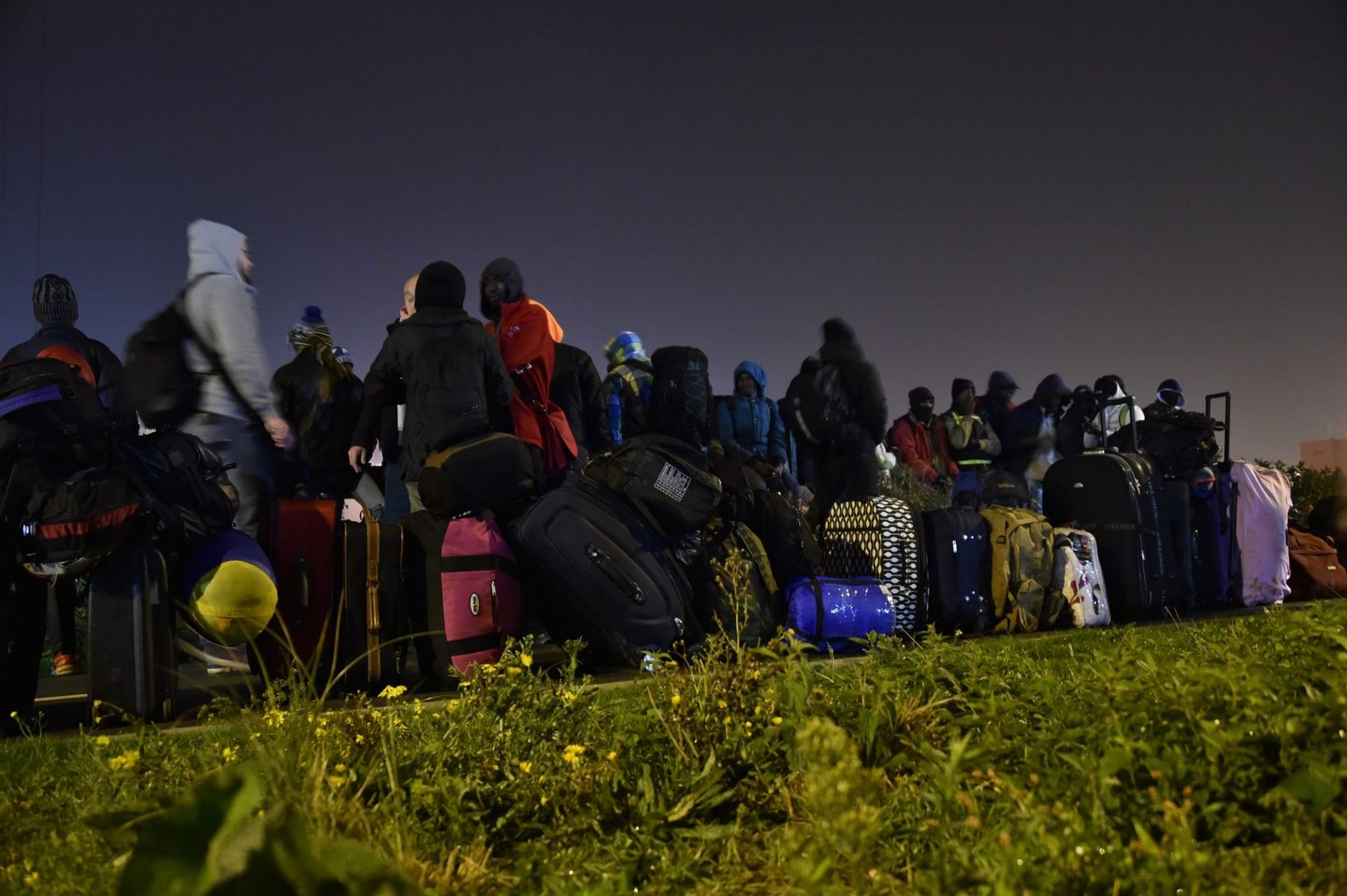 Migrants queue for transportation by bus to reception centres across France, from the "Jungle" migrant camp in Calais, northern France, on October 24, 2016. French authorities are set to begin on October 24, 2016 moving thousands of people out of the notorious Calais Jungle before demolishing the camp that has served as a launchpad for attempts to sneak into Britain. A major three-day operation is planned to clear the sprawling shanty town near Calais port -- a symbol of Europe's failure to resolve its migrant crisis -- of its estimated 6,000-8,000 occupants. The current Jungle camp dates from April 2015 and housed more than 10,000 migrants at its peak, although that number has dwindled to around 5,000 in its final days. / AFP / PHILIPPE HUGUEN (Photo credit should read PHILIPPE HUGUEN/AFP/Getty Images)
