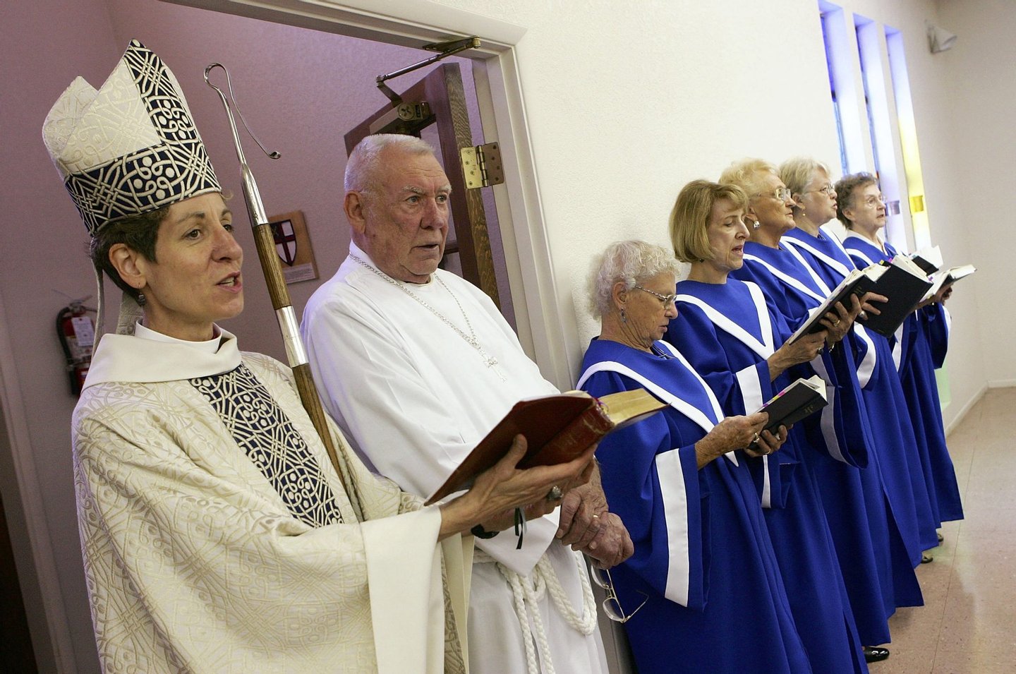 BULLHEAD CITY, AZ - JULY 02: Bishop Katharine Jefferts Schori (L) and chalice bearer Dick Studeny (2nd L) sing during the recessional of a service at The Episcopal Church of the Holy Spirit July 2, 2006 in Bullhead City, Arizona. Schori is the first female presiding bishop-elect for the Episcopal Church. (Photo by Ethan Miller/Getty Images)
