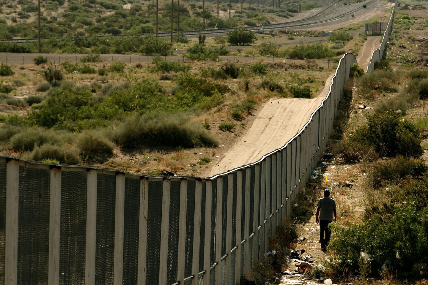 CIUDAD JUAREZ, CHIHUAHUA - JUNE 29: A man walks along the border fence between the U.S. and Mexico on June 29, 2007 in the Anapra area of Ciudad Juarez, Mexico. This area is a popular crossing spot for immigrants to ilegally cross into the United States because houses are close to the border on the south side and the highway is close to the north side. (Photo by Chip Somodevilla/Getty Images)