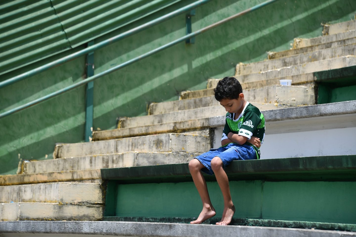 A boy sits alone on the stands during a tribute to the players of Brazilian team Chapecoense Real who were killed in a plane accident in the Colombian mountains, at the club's Arena Conda stadium in Chapeco, in the southern Brazilian state of Santa Catarina, on November 29, 2016. Players of the Chapecoense were among 81 people on board the doomed flight that crashed into mountains in northwestern Colombia, in which officials said just six people were thought to have survived, including three of the players. Chapecoense had risen from obscurity to make it to the Copa Sudamericana finals scheduled for Wednesday against Atletico Nacional of Colombia.  / AFP / Nelson ALMEIDA        (Photo credit should read NELSON ALMEIDA/AFP/Getty Images)