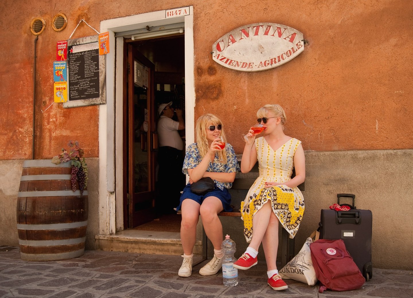 VENICE, ITALY - JUNE 17: Two tourists enjoy a Spritz (a powerful mixture of white wine, Campari and soda water) in front of a traditiona bacaro on June 17, 2011 in Venice, Italy. The bacari are the local down to earth version of wine bars which serve 'ciccheti, a kind of Tapas traditionally washed down with a glass of wine, and Venetians stop to snack and socialize before and after meals. (Photo by Marco Secchi/Getty Images)
