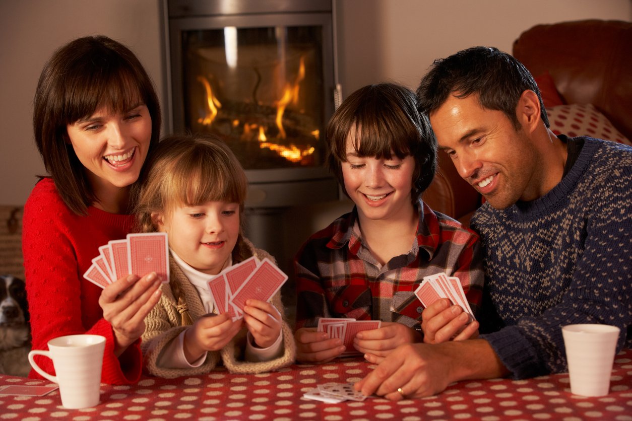 40s, 6-7 Years, 8-9 Years, Adult, Cards, Casual, Caucasian, Cheerful, Child, Comfortable, Daughter, Domestic Life, European Alps, Father, Female, Fire, Flame, Four People, France, Front View, Fun, Happiness, Heat, Home Interior, Indoors, Leisure Games, Little Boys, Little Girls, Log Fire, Mature Adult, Mother, People, Playing, Relaxation, Samoens, Sitting, Smiling, Sofa, Son, Togetherness, Winter, Women, woodburner,