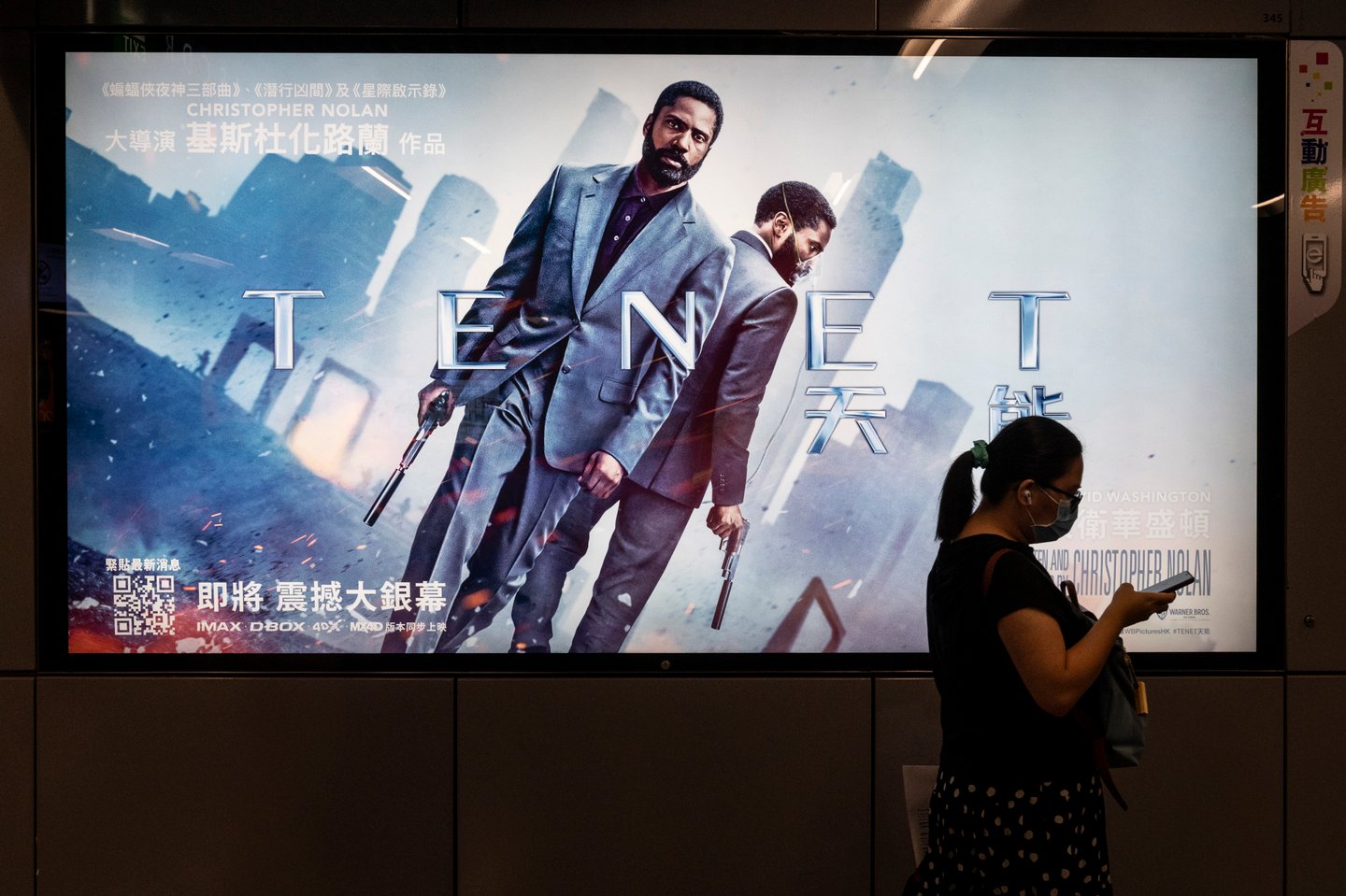 A commuter walks past a poster of Christopher Nolan's