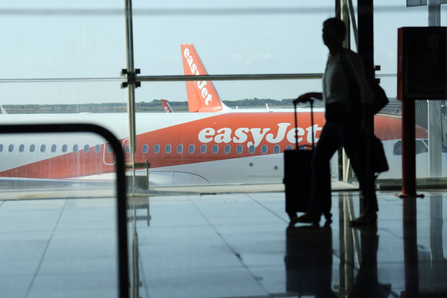 epa10116908 A man walks past an EasyJet plane at El Prat airport, Barcelona, Spain, 12 August 2022. The first day of the EasyJet pilots' strike in August has caused cancellations at El Prat and in Palma de Mallorca Airports. EPA/ALEJANDRO GARCIA