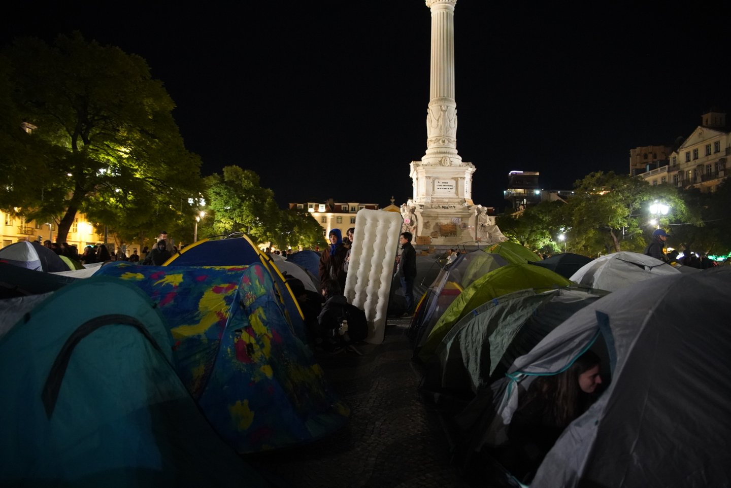 Fotografía real de la acampada de protesta por la vivienda en Rossio, Lisboa, la noche del 24 al 25 de octubre de 2026.